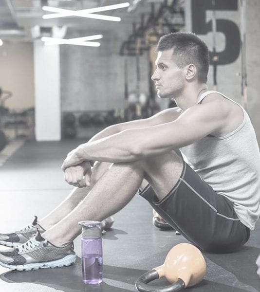 תמונה של מתעמל מדוכדך הסובל מאימון יתר, מסמלת את ההשפעות השליליות של מאמץ יתר על הגוף והנפש. חשוב להכיר את סימני האזהרה לאימון יתר ולנקוט בצעדים הנכונים כדי לשמור על הבריאות ולהימנע מנזק ארוך טווח.